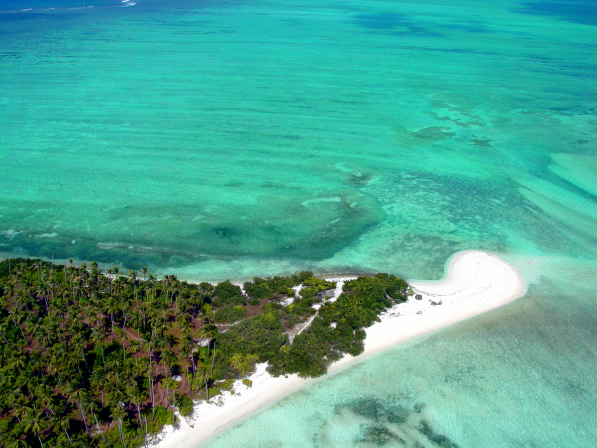 Aerial view of Kalpitti Island's northern tip beach, bordered by a shallow turquoise lagoon on three sides.